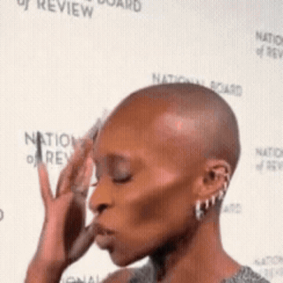 Woman With Shaved Head In Front Of Wall GIF