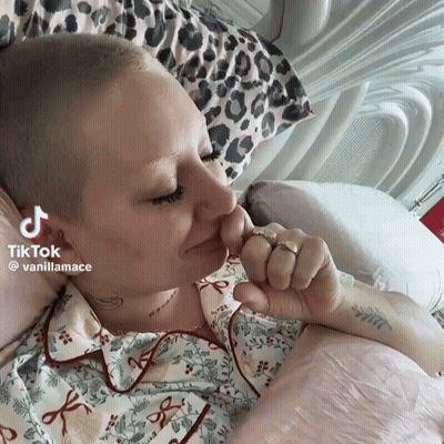 Woman With Shaved Head Laying On Bed TikTok Watermark GIF