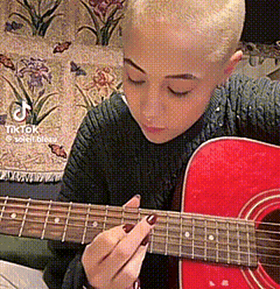 Woman With Shaved Head Playing Red Guitar Eyes Closed GIF