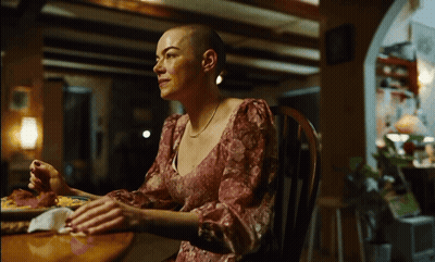 Woman With Shaved Head Sits At Table With Food GIF