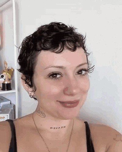 Woman With Short Curly Hair And Neck Tattoo Smiling GIF