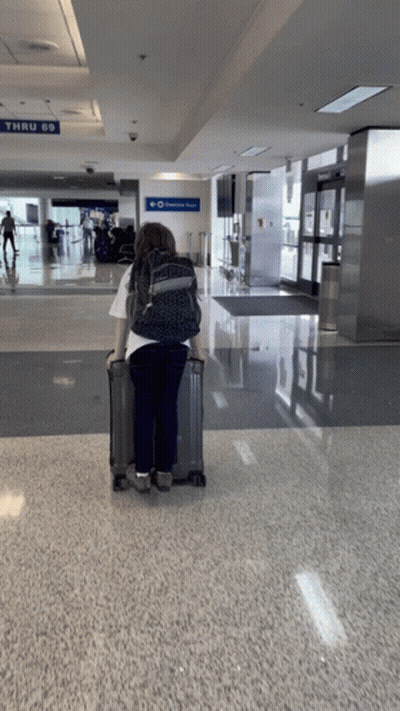 Woman With Suitcase At Airport Thru 69 Sign GIF