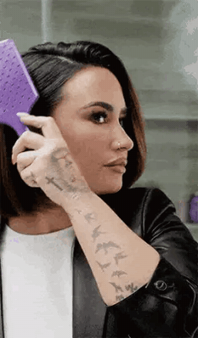 Woman With Tattoos Brushing Hair With Purple Brush GIF