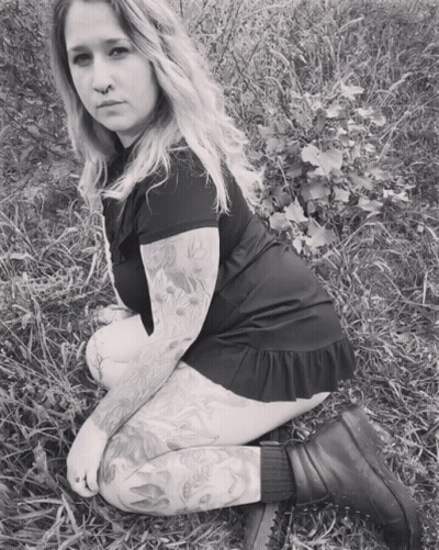 Woman With Tattoos Kneeling In Grass GIF