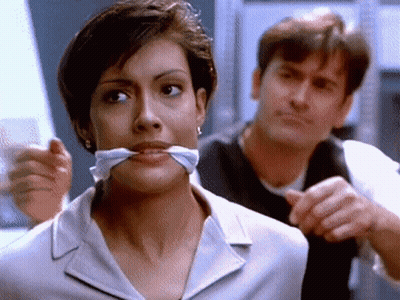 Woman With Tie Around Mouth Looking At Camera GIF