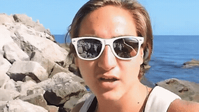 Woman With White Sunglasses On Rocky Shoreline GIF