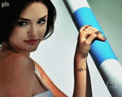 Woman With Wrist Tattoo Holding Blue And White Tube GIF