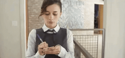 Woman Writing On Paper While Looking At Phone GIF