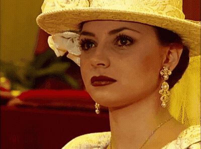 Woman Yellow Hat Pearl Earrings Looking At Camera GIF