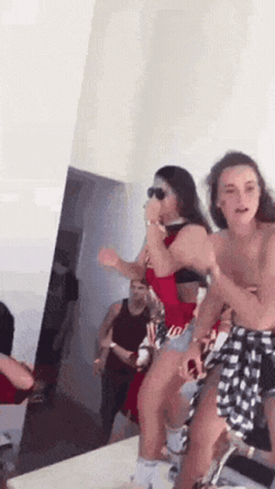 Women Dancing In A Room With Man In Background GIF