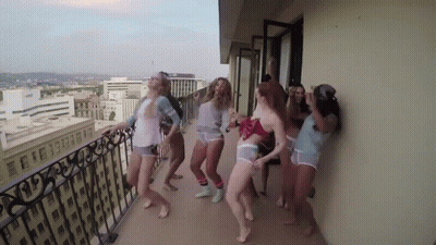 Women Dancing On Balcony Overlooking City GIF