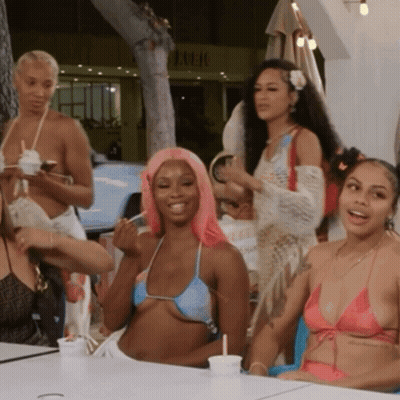 Women In Bikinis At Table In Front Of Lulu Sign GIF
