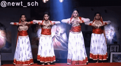 Women Performing In Front Of Newt Sch Sign GIF
