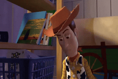 Woody From Toy Story Stands In Front Of A Shelf With Books On It GIF