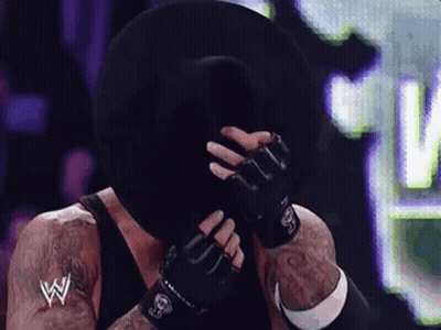 Wrestler Covering Face With Black Hat And Gloves GIF
