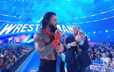 Wrestler Holding Belt In Front Of Wrestlemania Sign GIF