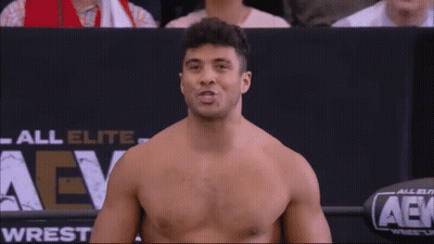 Wrestler Holding Belt In Front Of Wrestlemania Sign GIF