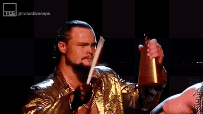 Wrestler In Gold Jacket Holding Bell And Sword GIF