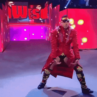 Wrestler In Red Coat Standing In Front Of Wes Sign GIF