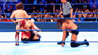 Wrestler Kneeling In Ring And Opponent Standing GIF