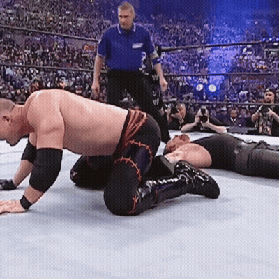 Wrestler Kneeling In Ring While Another Wrestler Lays On Ground GIF