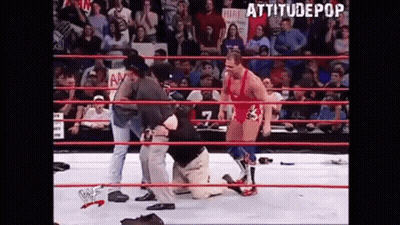 Wrestler Kneeling In Ring With Referee Behind GIF