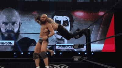 Wrestler Lifted By Another Wrestler In Front Of Danhaus Screen GIF