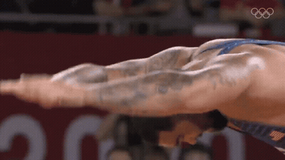 Wrestler Stretching Arms In Front Of Olympic Logo GIF