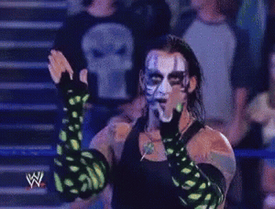 Wrestler With Green Gloves And Skull Shirt In Front Of Crowd GIF