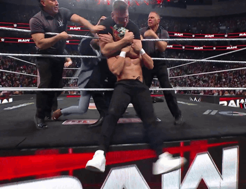 Wrestlers In A Wrestling Ring With The Word Raw On The Wall GIF
