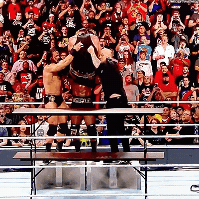 Wrestlers Standing On Table As Crowd Watches GIF