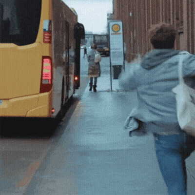 Yellow Bus Driving Past Bahnhof Sign GIF