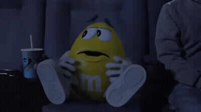 Yellow M&M Sitting In Movie Theater GIF