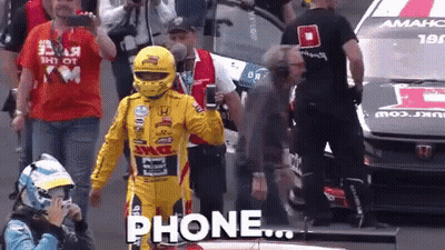 Yellow Racing Suit Man Holding Phone In Front Of Car GIF
