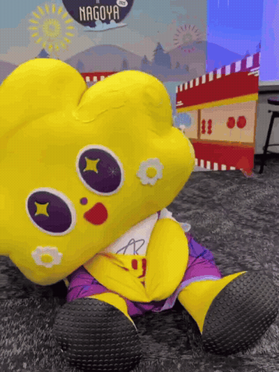 Yellow Stuffed Animal In Front Of Nagoya Sign GIF