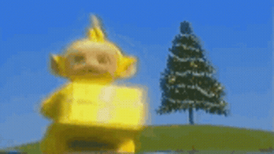 Yellow Teletubbies Carrying Box In Front Of Christmas Tree GIF