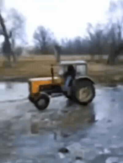 Yellow Tractor Driving Through Icy Puddle GIF