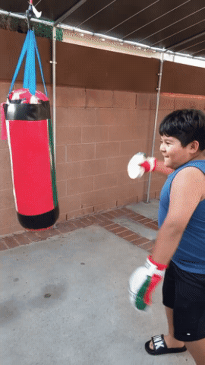 Young Boy Hitting Red Punching Bag With Boxing Gloves GIF