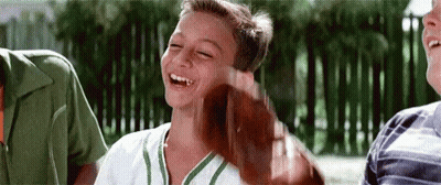 Young Boy In Baseball Uniform Laughing Holding Bat GIF