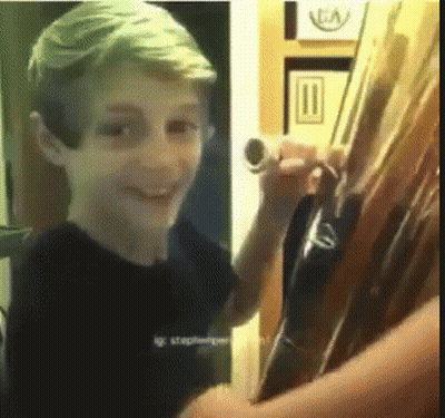 Young Boy In Black Shirt Smiling Holding Tube GIF