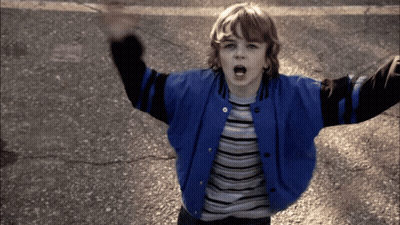 Young Boy In Blue And Black Varsity Jacket Arms Up GIF