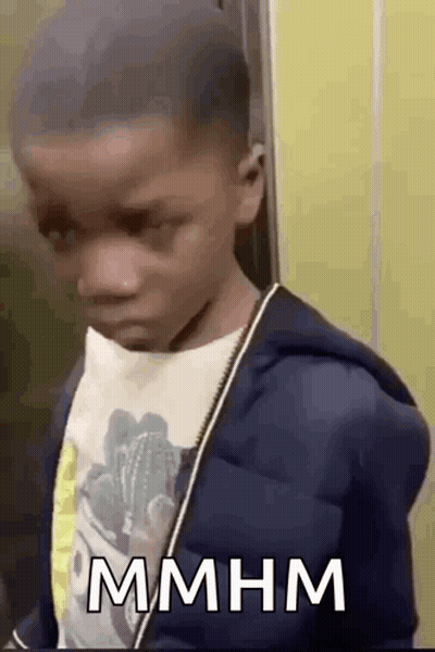 Young Boy In Blue Jacket And White Shirt In Front Of Yellow Wall GIF
