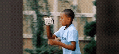 Young Boy In Blue Shirt Playing With Remote Control GIF