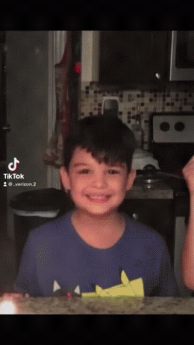 Young Boy In Blue Shirt Smiling In Front Of Microwave And Stove GIF