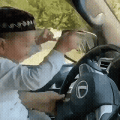 Young Boy In Driver's Seat Holding Steering Wheel GIF
