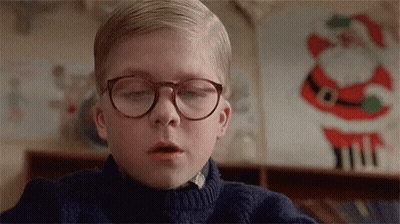 Young Boy In Glasses And Blue Sweater Beside Santa Claus Decoration GIF