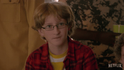 Young Boy In Glasses And Plaid Shirt Sitting At Table GIF