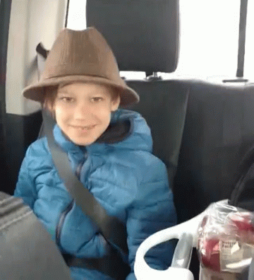 Young Boy In Hat And Blue Jacket Sitting In Back Seat Of Car GIF