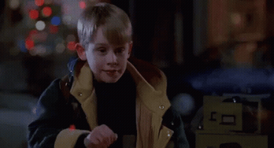 Young Boy In Jacket In Front Of Christmas Tree In Dark Room GIF