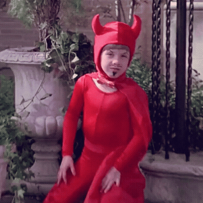 Young Boy In Red Devil Costume Standing In Front Of Planter GIF